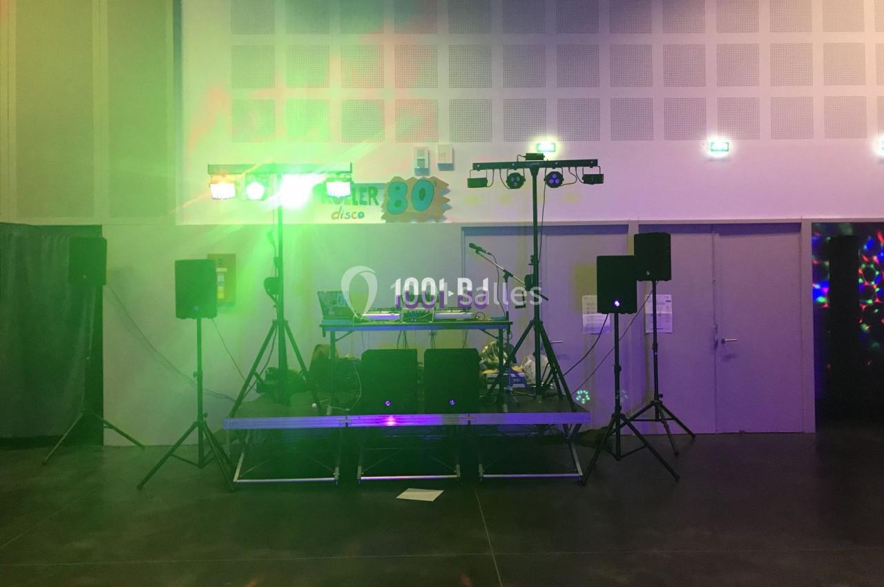 Installation de matériel de DJ avec lumières colorées sur une scène dans une salle de fête.