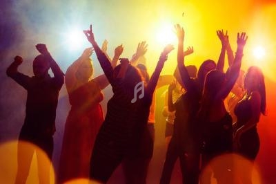 Groupe de personnes dansant sous des lumières colorées dans une ambiance festive.