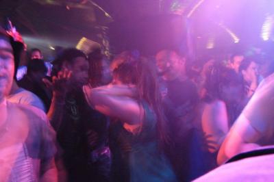 Groupe de personnes dansant sous des lumières colorées dans une ambiance festive.