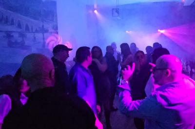 Groupe de personnes dansant sous des lumières colorées dans une ambiance festive.