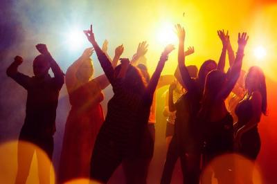 Groupe de personnes dansant sous des lumières colorées dans une ambiance festive.