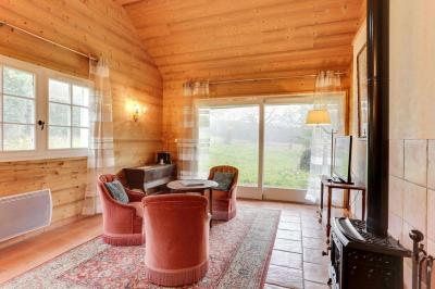 Chambre avec murs en bois, lit simple, bureau, fenêtre avec rideaux fleuris et lumière naturelle.