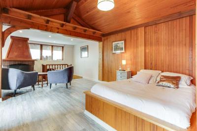 Chambre avec murs en bois, lit simple, bureau, fenêtre avec rideaux fleuris et lumière naturelle.