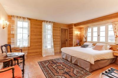Chambre avec murs en bois, lit simple, bureau, fenêtre avec rideaux fleuris et lumière naturelle.