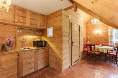 Chambre avec murs en bois, lit simple, bureau, fenêtre avec rideaux fleuris et lumière naturelle.
