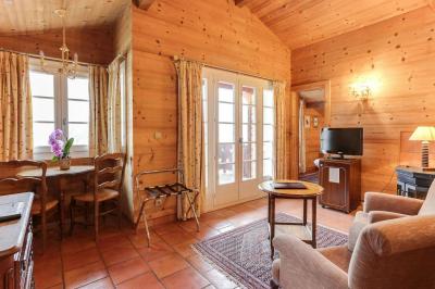 Chambre avec murs en bois, lit simple, bureau, fenêtre avec rideaux fleuris et lumière naturelle.