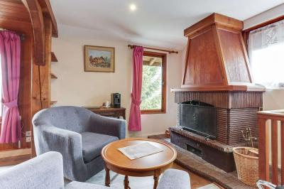 Chambre avec murs en bois, lit simple, bureau, fenêtre avec rideaux fleuris et lumière naturelle.