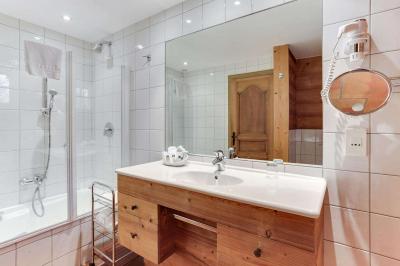 Chambre avec murs en bois, lit simple, bureau, fenêtre avec rideaux fleuris et lumière naturelle.
