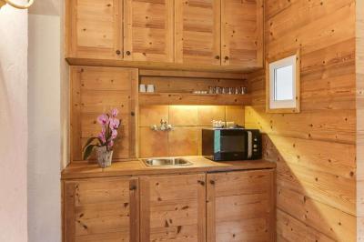 Chambre avec murs en bois, lit simple, bureau, fenêtre avec rideaux fleuris et lumière naturelle.