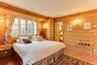 Chambre avec murs en bois, lit simple, bureau, fenêtre avec rideaux fleuris et lumière naturelle.