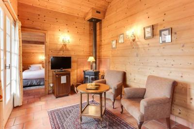 Chambre avec murs en bois, lit simple, bureau, fenêtre avec rideaux fleuris et lumière naturelle.
