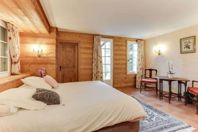 Chambre avec murs en bois, lit simple, bureau, fenêtre avec rideaux fleuris et lumière naturelle.