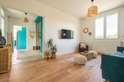 Tables et chaises en bois disposées en extérieur près d'une rivière, avec parasols et végétation en arrière-plan.