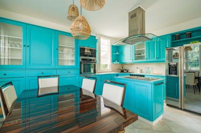 Tables et chaises en bois disposées en extérieur près d'une rivière, avec parasols et végétation en arrière-plan.