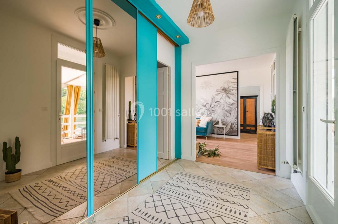 Entrée lumineuse avec placards à portes miroir, tapis à motifs géométriques et vue sur un salon et une terrasse.