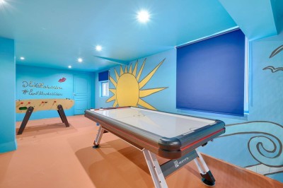 Tables et chaises en bois disposées en extérieur près d'une rivière, avec parasols et végétation en arrière-plan.