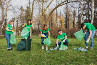 Des bénévoles ramassent des déchets en plastique dans un parc, utilisant des sacs verts et des gants pour nettoyer l…