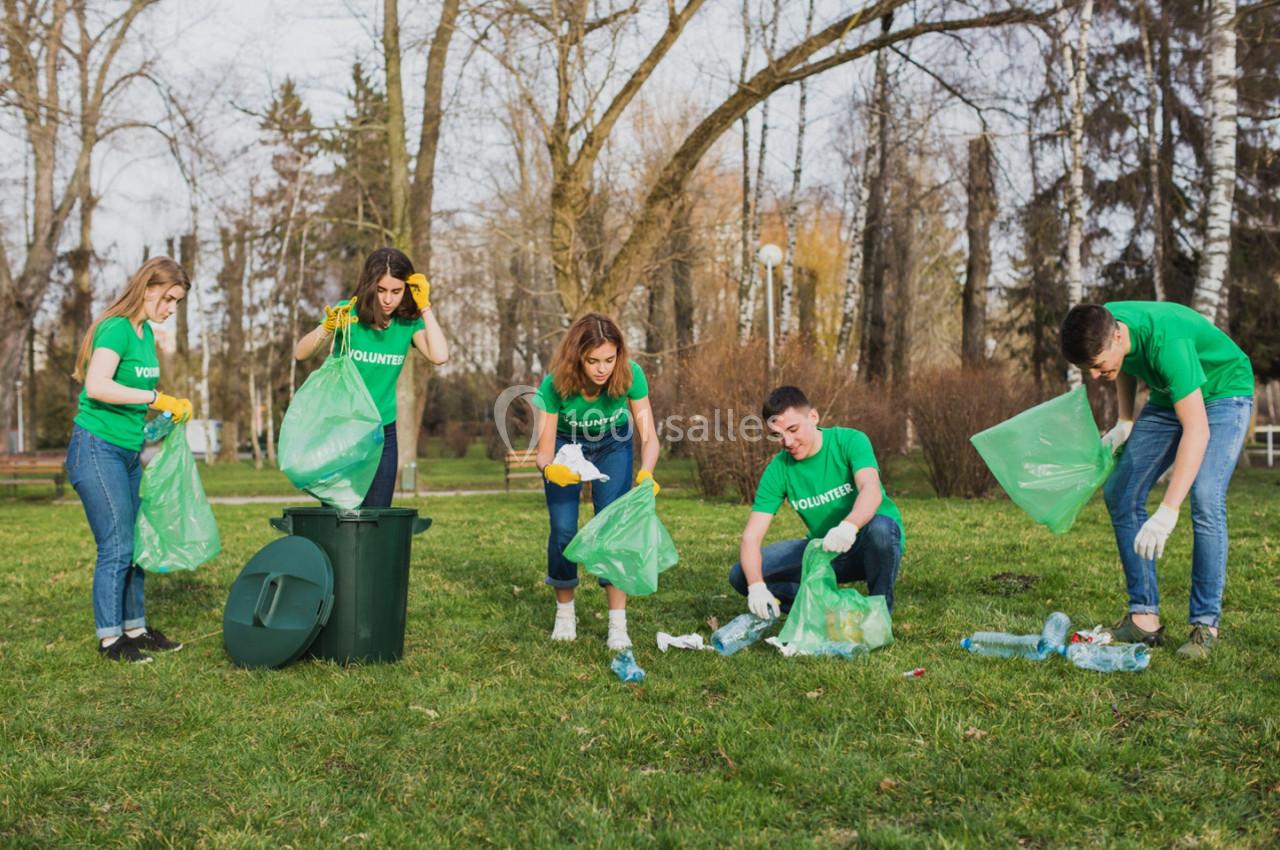 Des bénévoles ramassent des déchets en plastique dans un parc, utilisant des sacs verts et des gants pour nettoyer l…