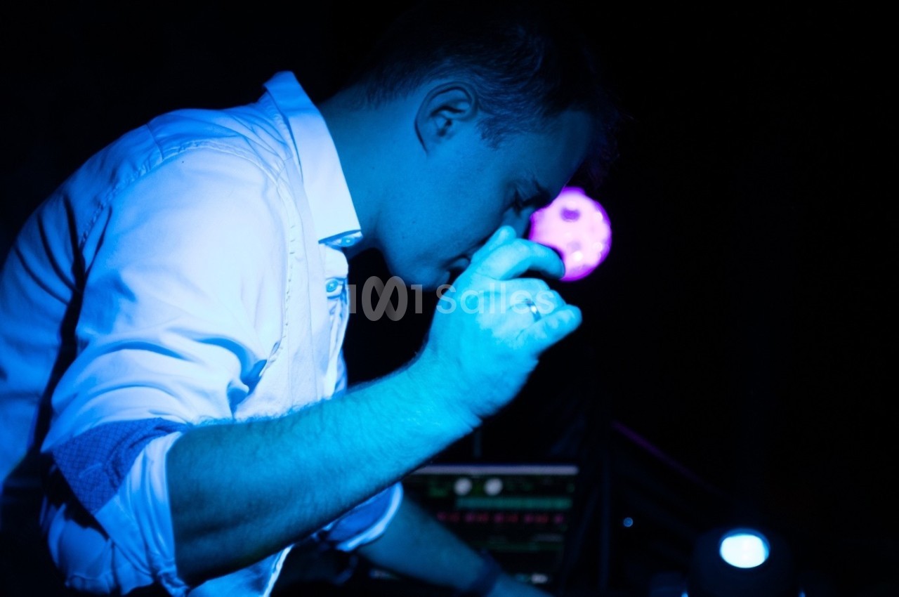 Un homme en chemise blanche, éclairé par une lumière bleue, semble concentré devant un équipement électronique.