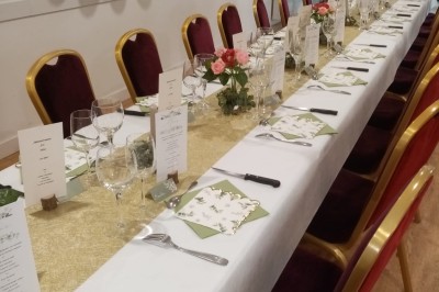 Personnes rassemblées sous une tente blanche lors d'un événement en extérieur, discutant et se servant des boissons.