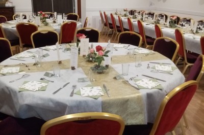 Personnes rassemblées sous une tente blanche lors d'un événement en extérieur, discutant et se servant des boissons.