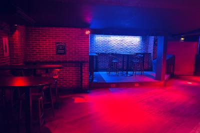 Un homme souriant avec des lunettes de soleil pose avec une femme dans un environnement festif et animé.