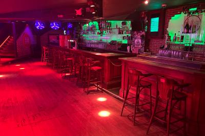 Un homme souriant avec des lunettes de soleil pose avec une femme dans un environnement festif et animé.