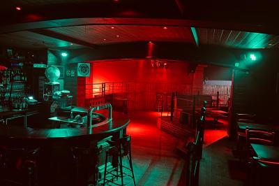 Un homme souriant avec des lunettes de soleil pose avec une femme dans un environnement festif et animé.