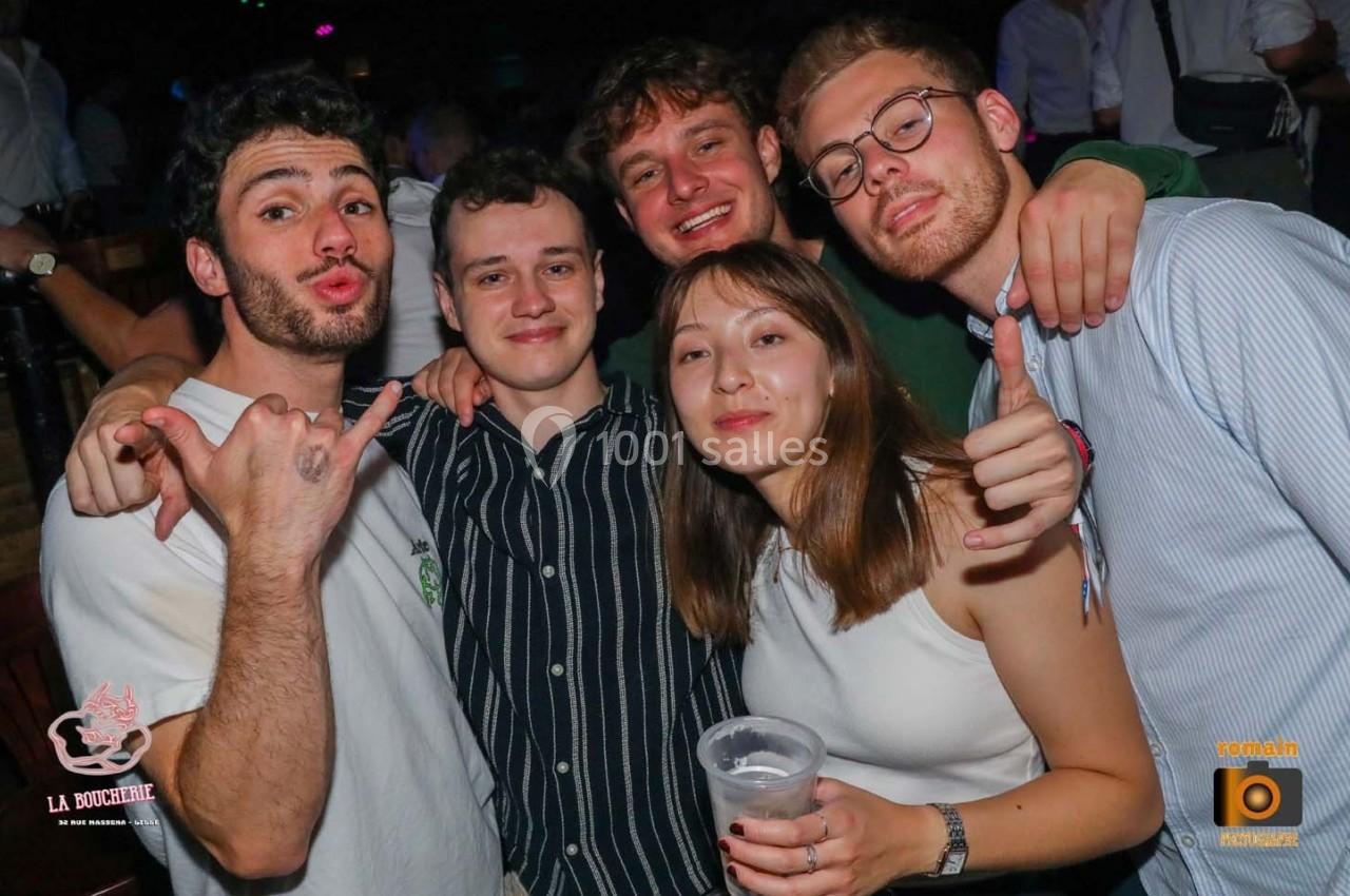 Un groupe de cinq jeunes adultes souriants posant ensemble dans un environnement festif.