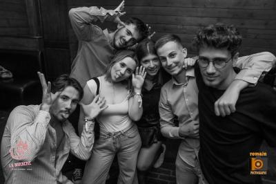 Un homme souriant avec des lunettes de soleil pose avec une femme dans un environnement festif et animé.