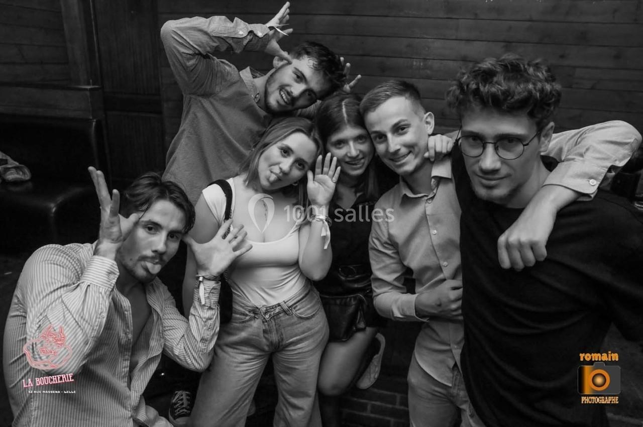 Un groupe de jeunes pose de manière décontractée et amusante dans un lieu intérieur avec un décor en bois.