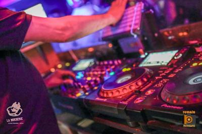 Un homme souriant avec des lunettes de soleil pose avec une femme dans un environnement festif et animé.