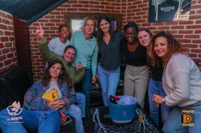 Un homme souriant avec des lunettes de soleil pose avec une femme dans un environnement festif et animé.