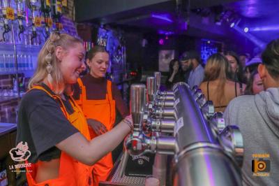 Un homme souriant avec des lunettes de soleil pose avec une femme dans un environnement festif et animé.