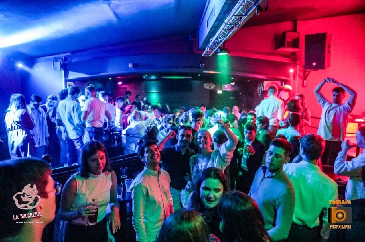 Groupe de personnes dans une ambiance festive et colorée, dans une salle de soirée animée.