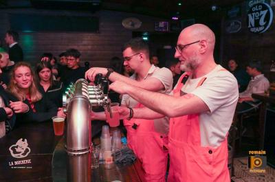 Un homme souriant avec des lunettes de soleil pose avec une femme dans un environnement festif et animé.