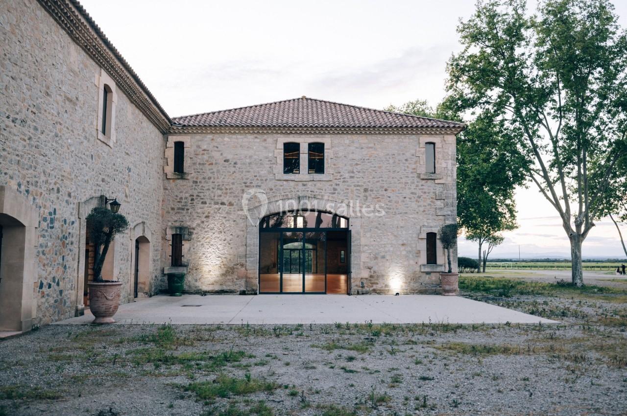 Bâtiment en pierre avec une grande porte vitrée, entouré d'arbres et situé dans un environnement rural.