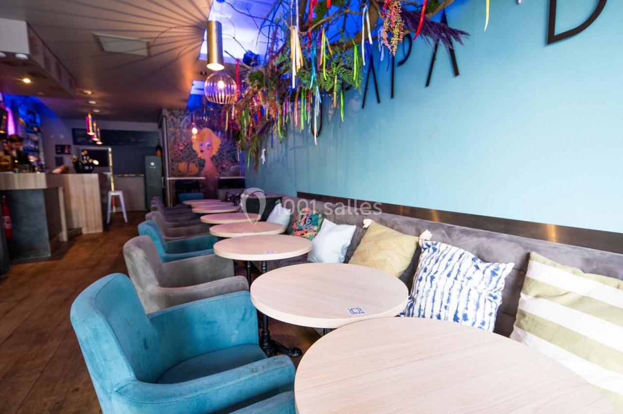 Salle de café moderne avec des tables rondes, des fauteuils colorés et une décoration murale végétale.