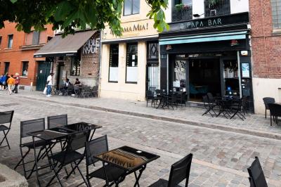 Terrasse vide de cafés et restaurants sur une rue pavée bordée de bâtiments en briques et en pierre.