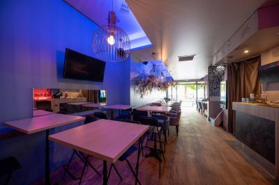 Terrasse vide avec tables et chaises noires sur une rue pavée, devant des façades de cafés et restaurants.