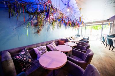 Terrasse vide avec tables et chaises noires sur une rue pavée, devant des façades de cafés et restaurants.