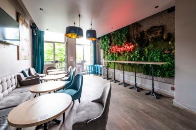 Terrasse vide avec tables et chaises noires sur une rue pavée, devant des façades de cafés et restaurants.