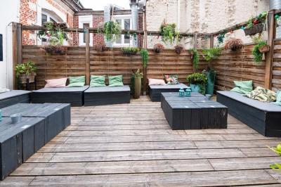 Terrasse vide avec tables et chaises noires sur une rue pavée, devant des façades de cafés et restaurants.