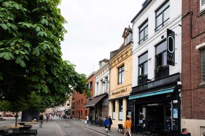 Terrasse vide avec tables et chaises noires sur une rue pavée, devant des façades de cafés et restaurants.
