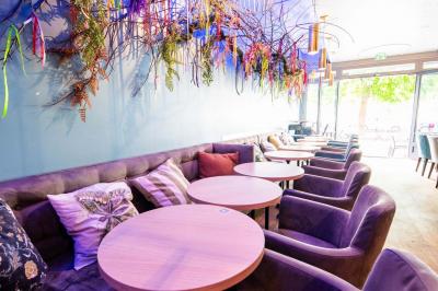 Terrasse vide avec tables et chaises noires sur une rue pavée, devant des façades de cafés et restaurants.