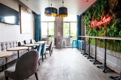 Terrasse vide avec tables et chaises noires sur une rue pavée, devant des façades de cafés et restaurants.