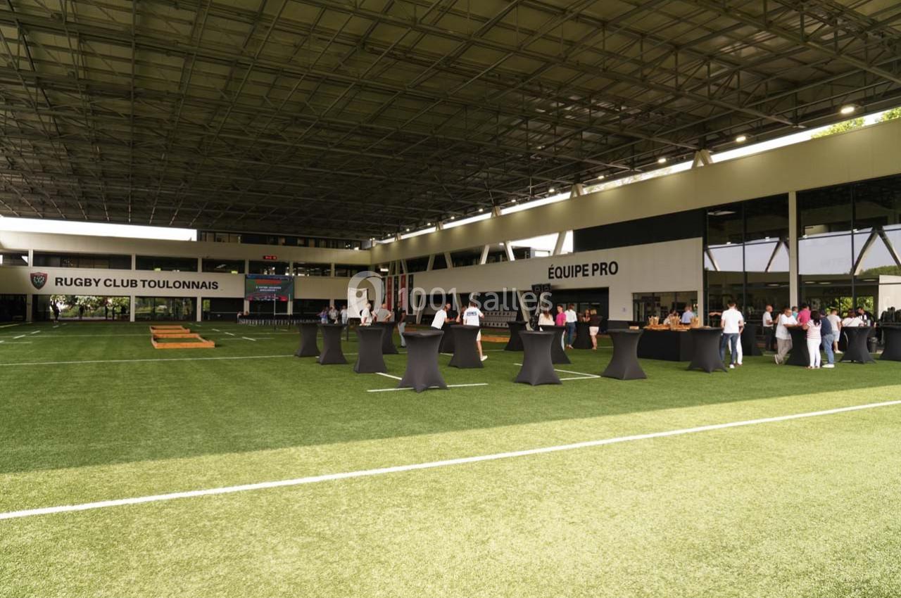 Terrains couverts avec des tables hautes et des groupes de personnes dans un centre d'entraînement sportif.