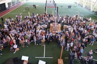 Table ronde en bois entourée de chaises à motifs rouges et blancs, située dans un jardin avec des plantes et des fleurs.