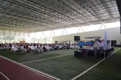 Table ronde en bois entourée de chaises à motifs rouges et blancs, située dans un jardin avec des plantes et des fleurs.