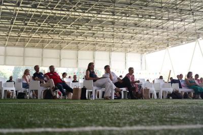Table ronde en bois entourée de chaises à motifs rouges et blancs, située dans un jardin avec des plantes et des fleurs.